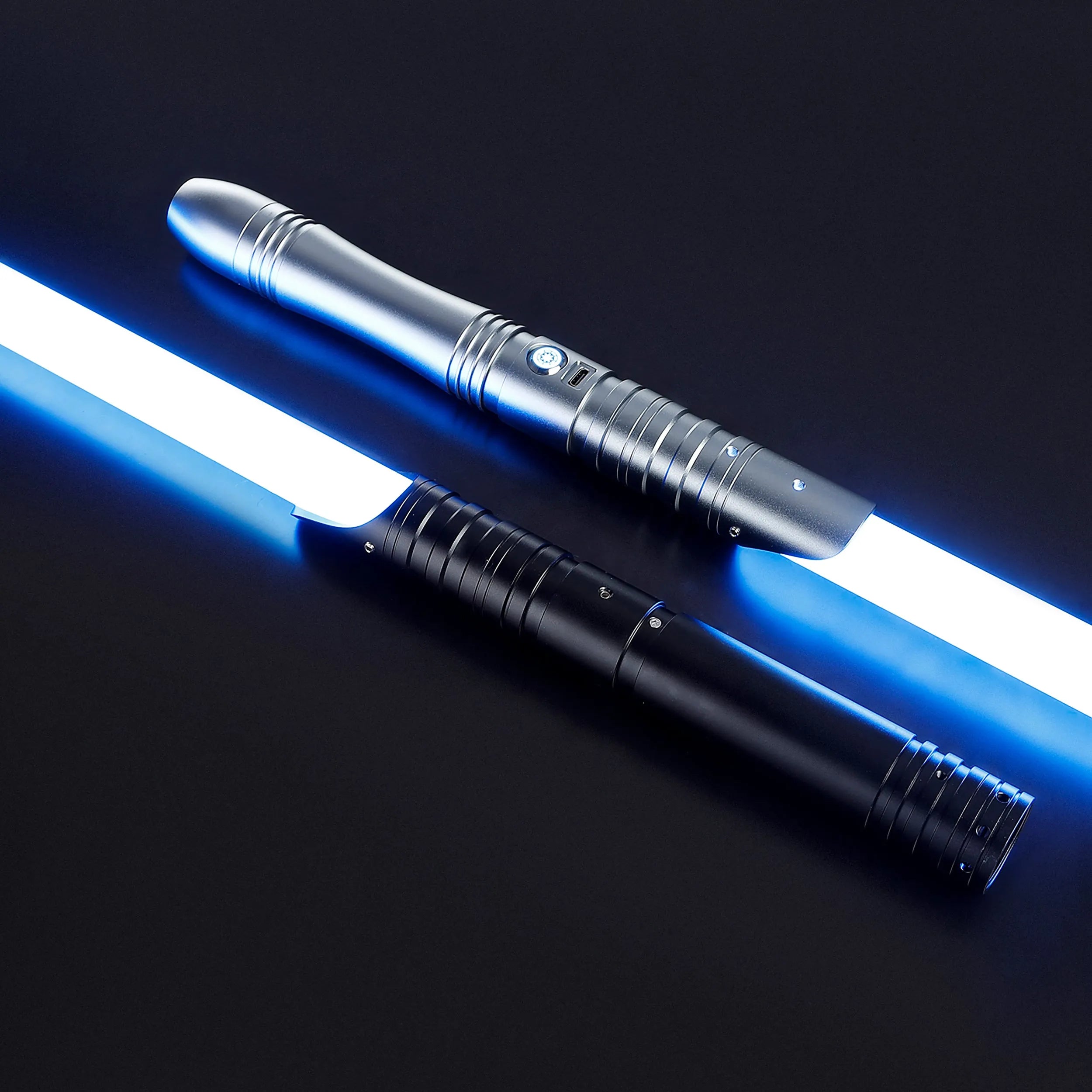 Two baselit sabers, one silver 36” and one black 32”, with glowing blue blades on a dark background.