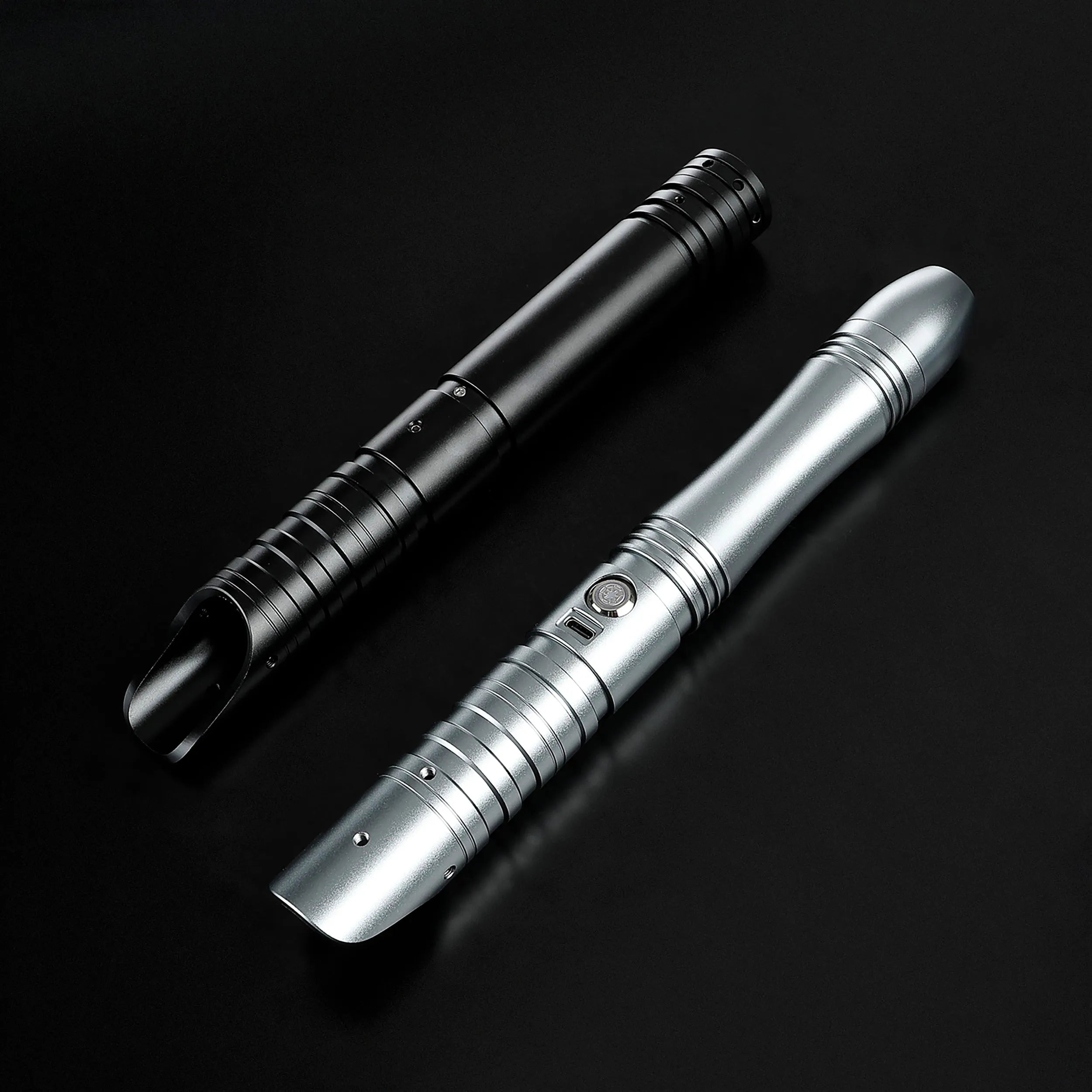 Two sleek aluminum saber hilts, one black and one silver, designed for father & son dueling.