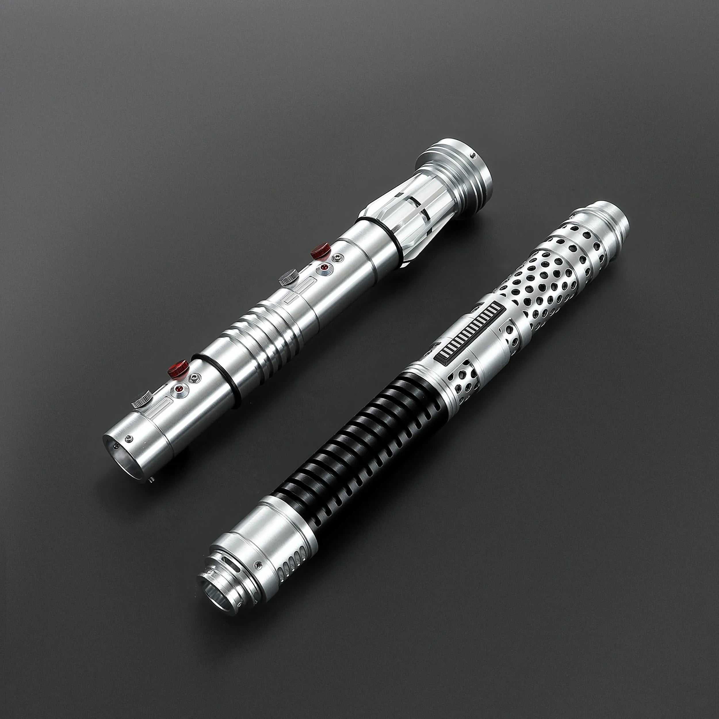 Two brushed silver metal Shadow Lord saber hilts with black grips and red buttons, designed for dual-blade combat.