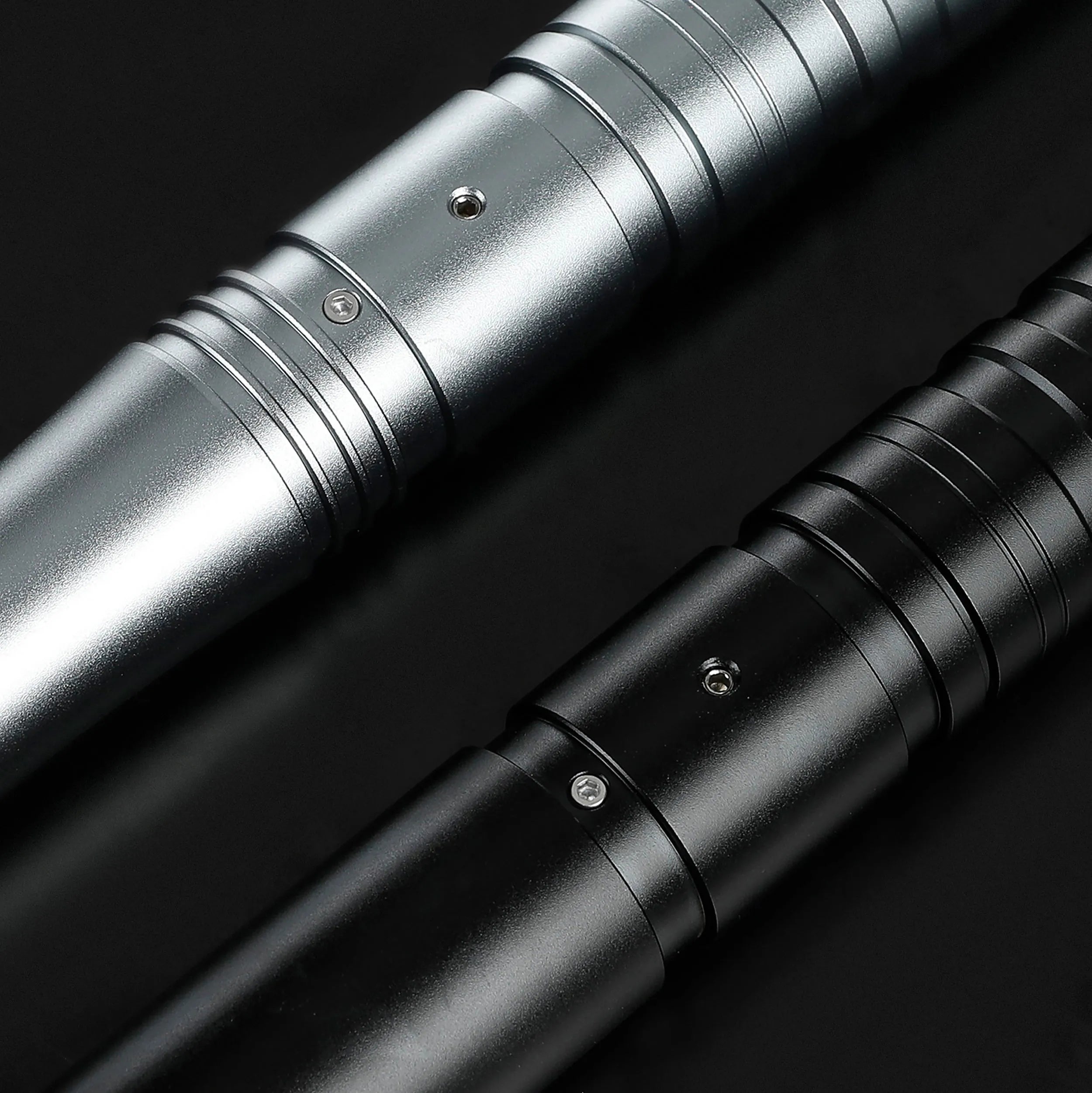 Close-up of two T6 aluminum alloy saber hilts, one silver and one black, with ribbed grips.
