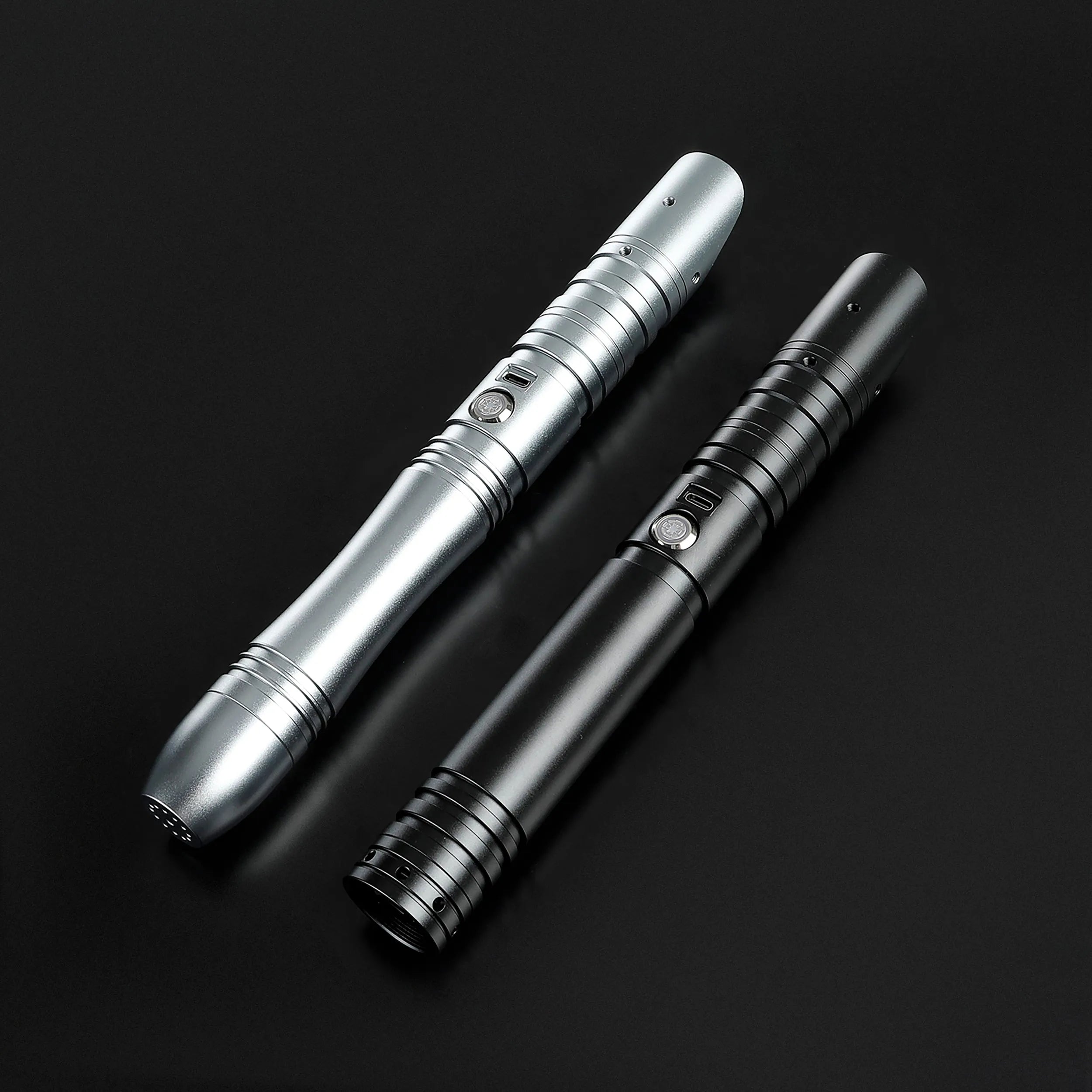 Two sleek aluminum saber hilts, one silver and one black, with ribbed grips and activation buttons.