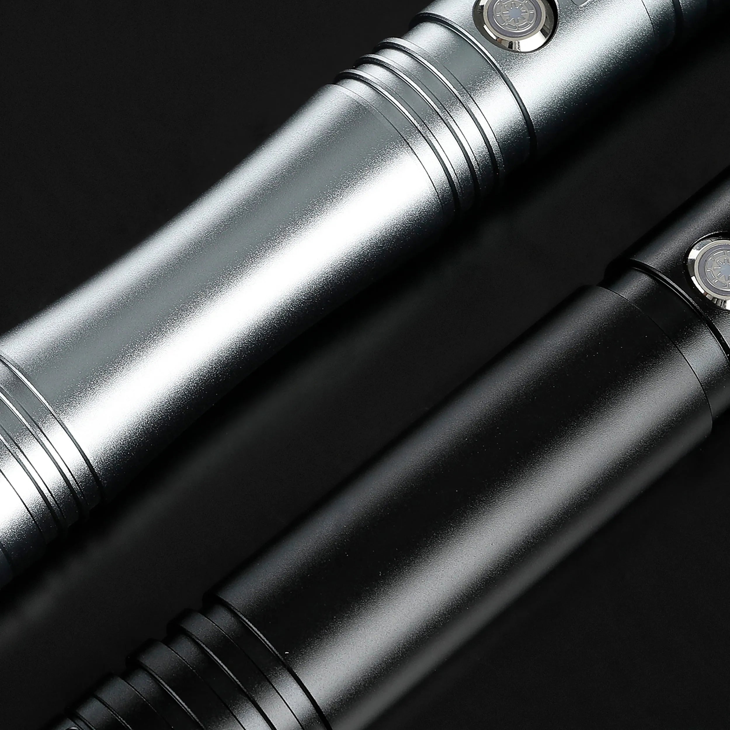 Two durable aluminum saber hilts, one silver and one black, with illuminated buttons.