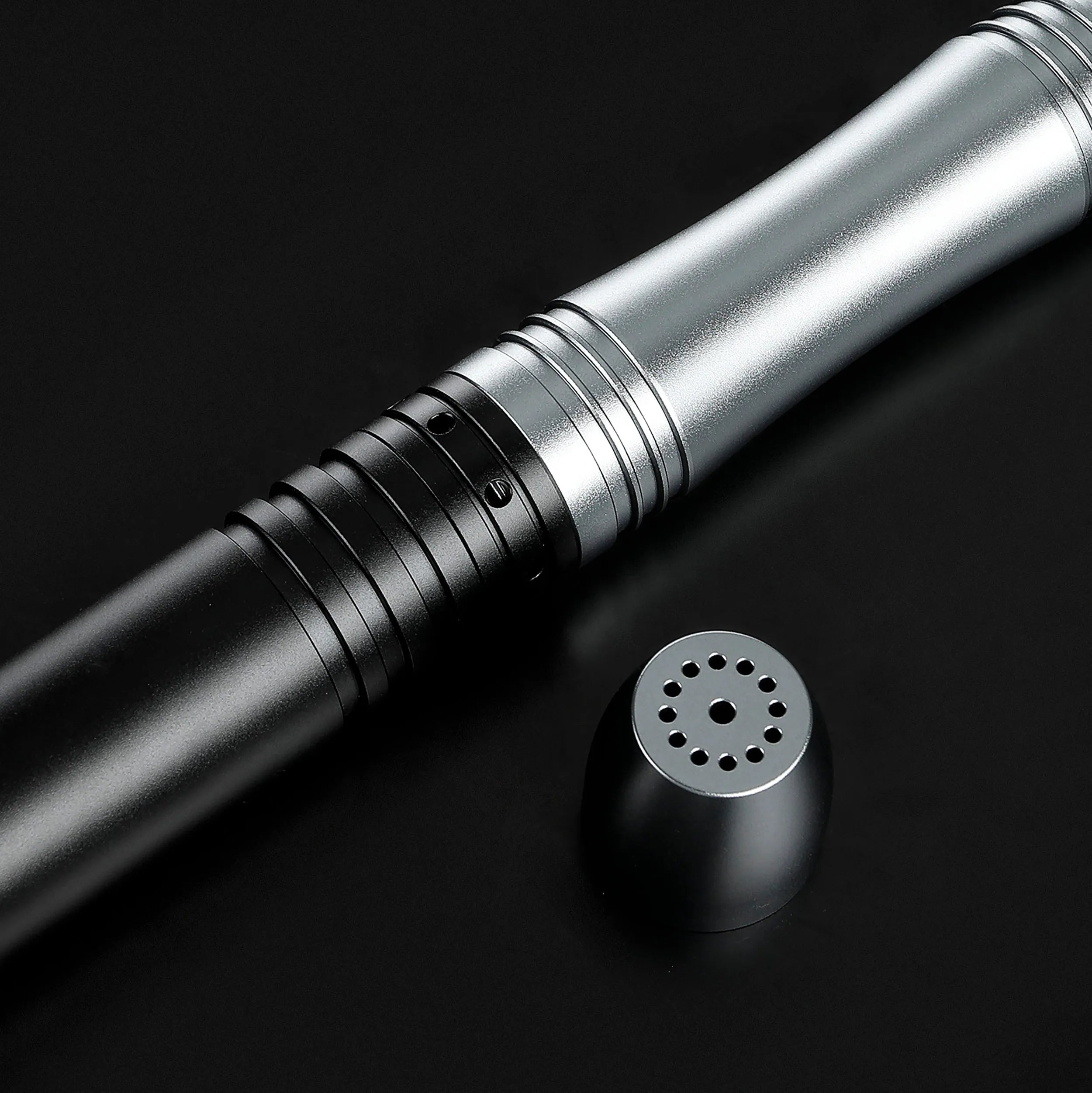 Close-up of a sleek black and silver aluminum saber hilt with a detached speaker pommel.