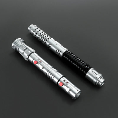 Two brushed silver metal Shadow Lord saber hilts, one with black grip and perforated design, the other with red buttons.