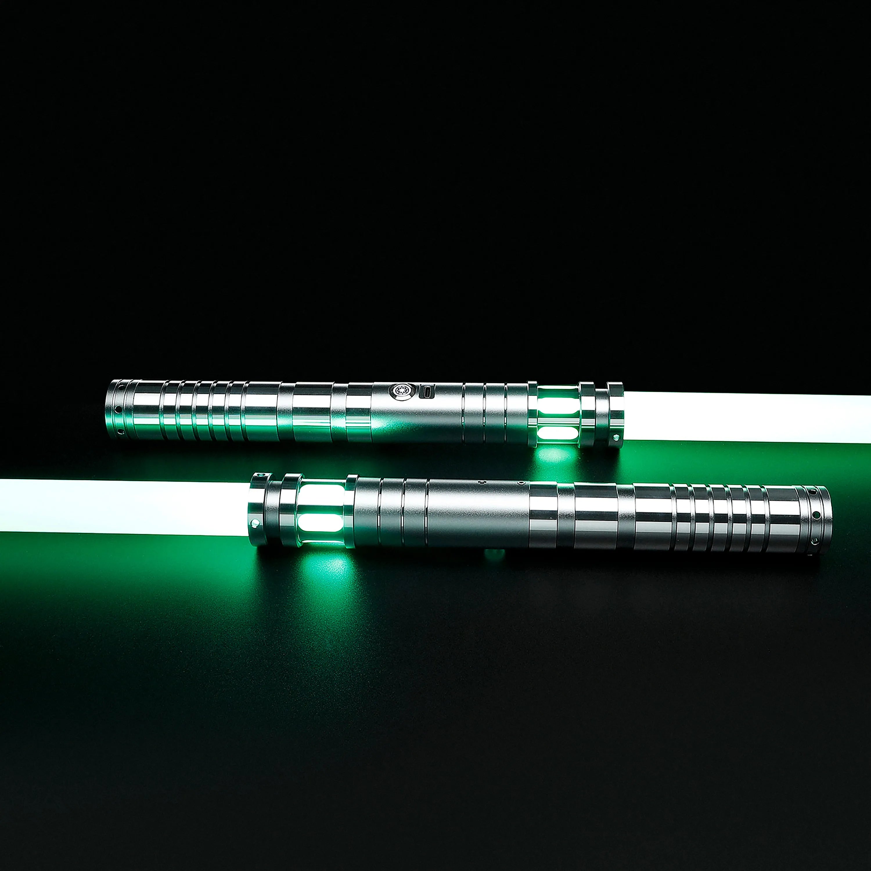 Two silver T6 aluminum Sol lightsabers with glowing green polycarbonate blades on a black background.