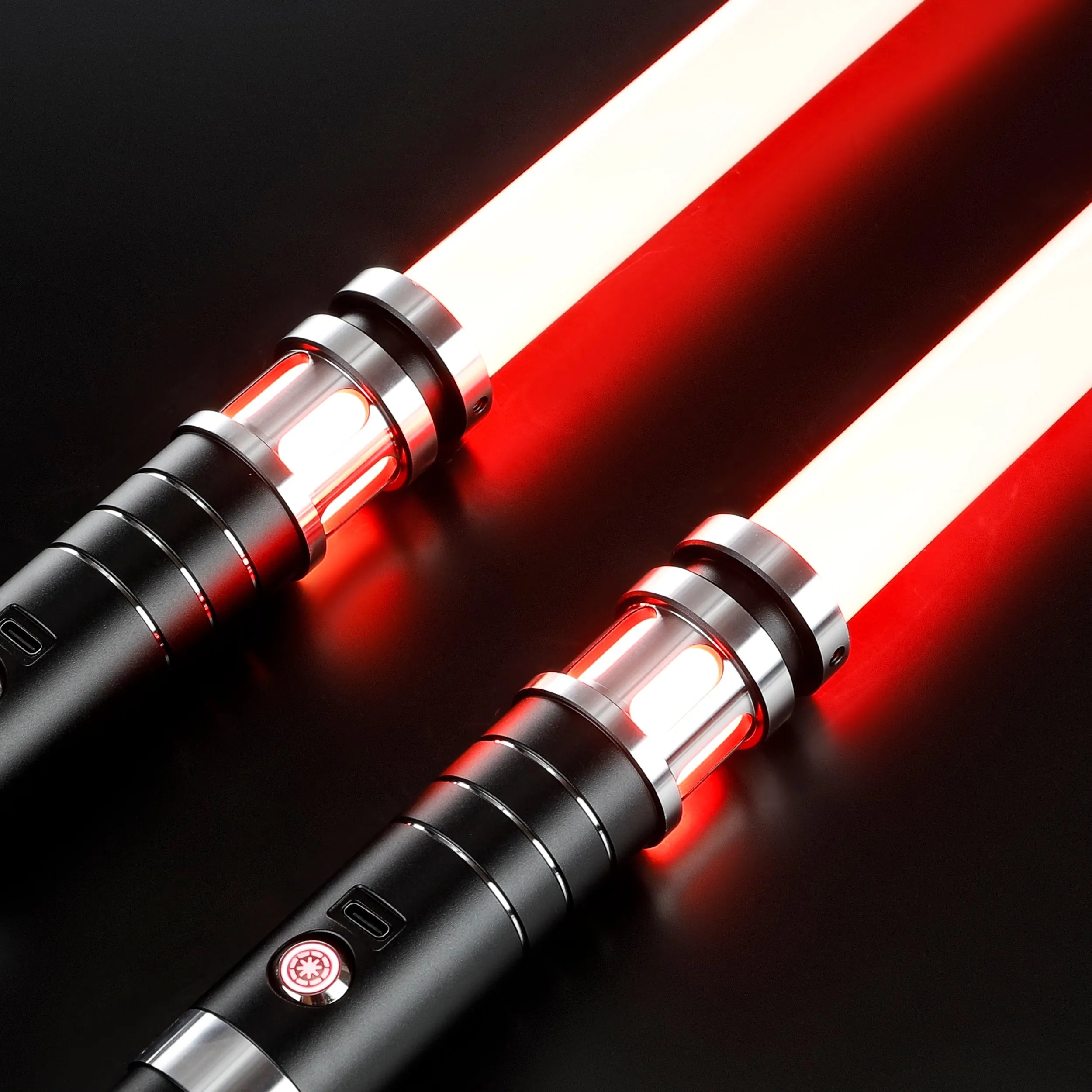 Two Sol lightsabers with black aluminum hilts and glowing red polycarbonate blades on a dark background.